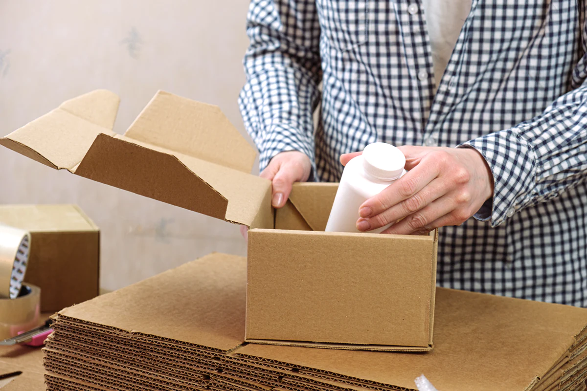woman warehouse is packing plastic jar with vitamins cardboard โรงงานผลิตกล่องกระดาษลูกฟูก,โรงงานผลิตกล่อง,รับผลิตกล่องกระดาษลูกฟูก,กล่องกระดาษลูกฟูก,กล่องสั่งผลิต,กล่องพิมพ์ลาย,กล่องคุณภาพดี